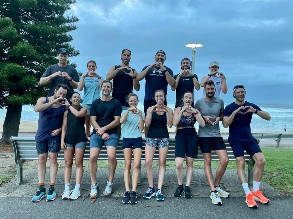 The Running2Explore crew making heart signs together on the Bondi beachfront after a group run